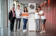 Vier Jugendliche und ein Mann, die in einem Gang stehen mit ihrem Produkt und einem Zertifikat in der Hand