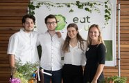 Vier Jugendliche stehen vor einem Ausstellungstisch und lächeln in die Kamera