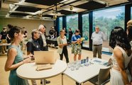 Menschen stehen an verschiedenen Tischen, andere schauen sich die präsentierten Ideen an