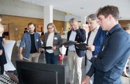 Eine Gruppe Menschen steht um einen Bildschirm und sieht sich etwas an