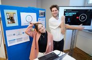 Zwei Menschen strecken sich und präsentieren ihr Start-up an ihrem Stand
