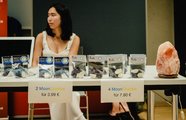 Eine Frau sitzt an ihrem Stand, auf dem Ausstellungstisch vor ihr liegt ihr Produkt
