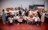 Eine große Gruppe Menschen, die in die Kamera lächelt und Zertifikate hochhält