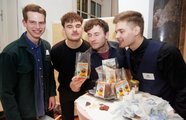 Vier Studierende riechen an einem Produkt und posieren für die Kamera