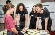 Lachende Jugendliche, die um einen Ausstellungstisch stehen
