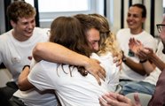 Ein Mann und eine Frau, die sich glücklich in den Arm nehmen mit lachenden Menschen um sie herum