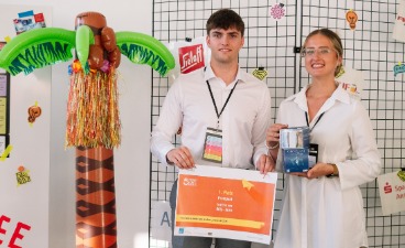 Foto der beiden Sieger des Wettbewerbs neben ein Deko-Palme